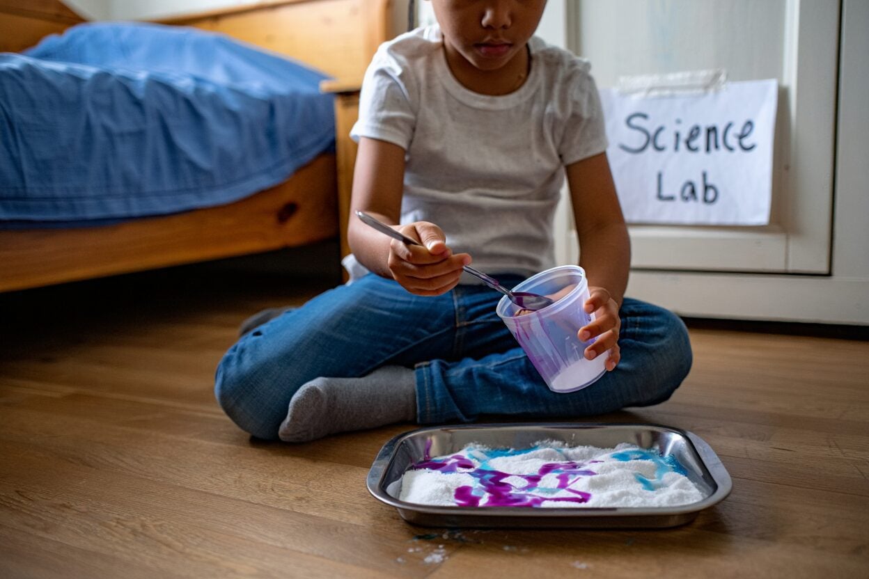 Child doing a science experiment with colored liquids and white powder.